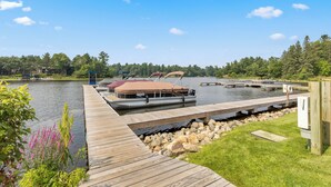 A dock with boats, a wooden pier, and a lake surrounded by trees. - Causeway on Gull (Nisswa)