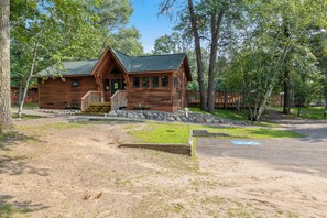 Une cabane en bois dotée d’une véranda, d’un escalier et d’une allée pavée.