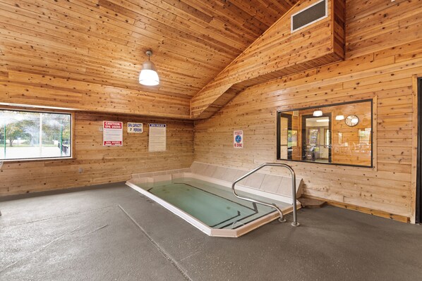 A wooden spa with a glass-enclosed hot tub, wooden walls, and a clock on the wall. - Causeway on Gull (Nisswa)