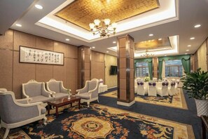 A hotel lobby with seating, a chandelier, a large rug, and a wall-mounted screen. - Huchuan Hotel (Yueqing)