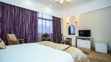 A hotel room with a large bed, a desk with a TV, and a chair.