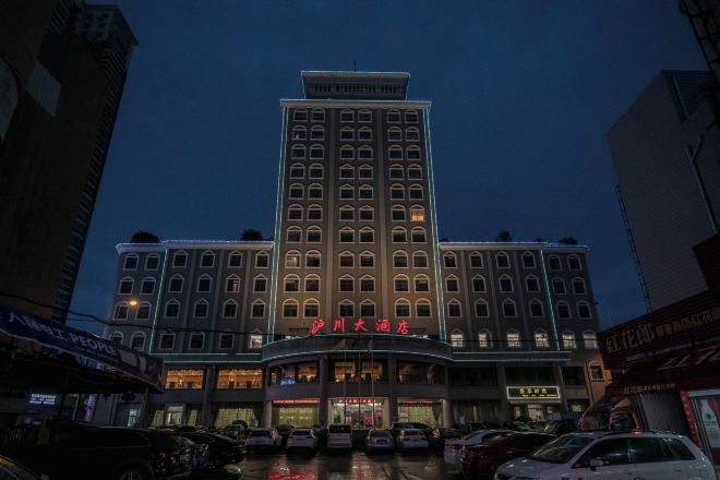 Um hotel com vários andares, entrada imponente e placas indicativas.