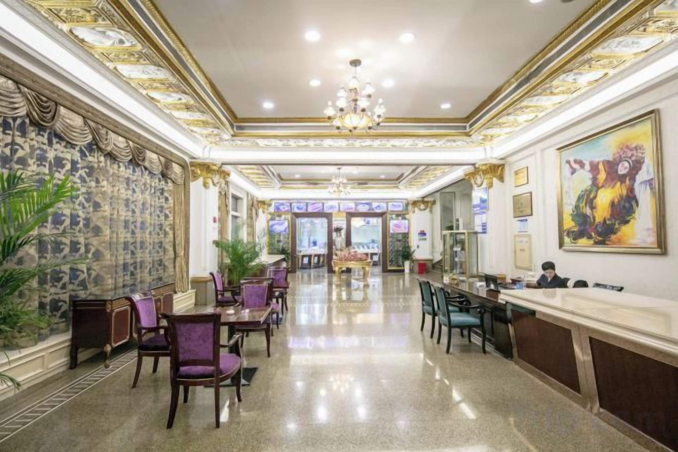 Un hall d’hôtel comprenant un comptoir d’accueil, un espace salon et un lustre.