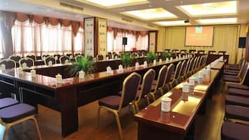 Un salón de conferencias con una larga mesa, sillas y una pantalla para proyector.