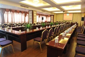 A conference room with a long table, chairs, and a projector screen.