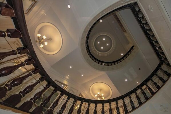 A spiral staircase with a circular design, multiple light fixtures, and a polished floor.