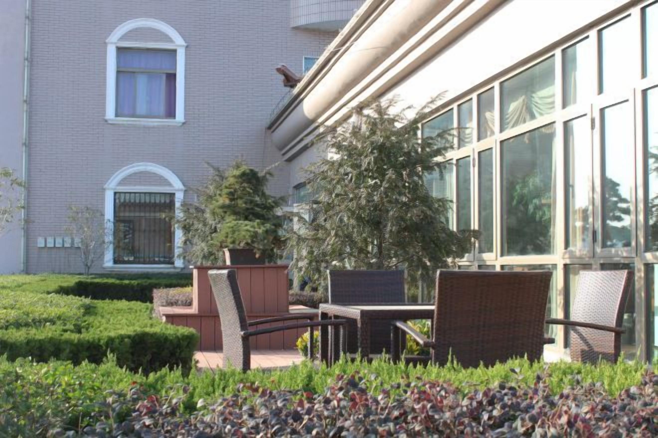 Un edificio con fachada de ladrillo, ventanas grandes y mesas y sillas para exteriores.