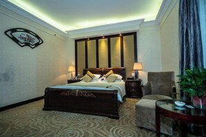 A hotel room with a large bed, two bedside tables with lamps, a chair, and a small table with a plant. - Huchuan Hotel (Yueqing)