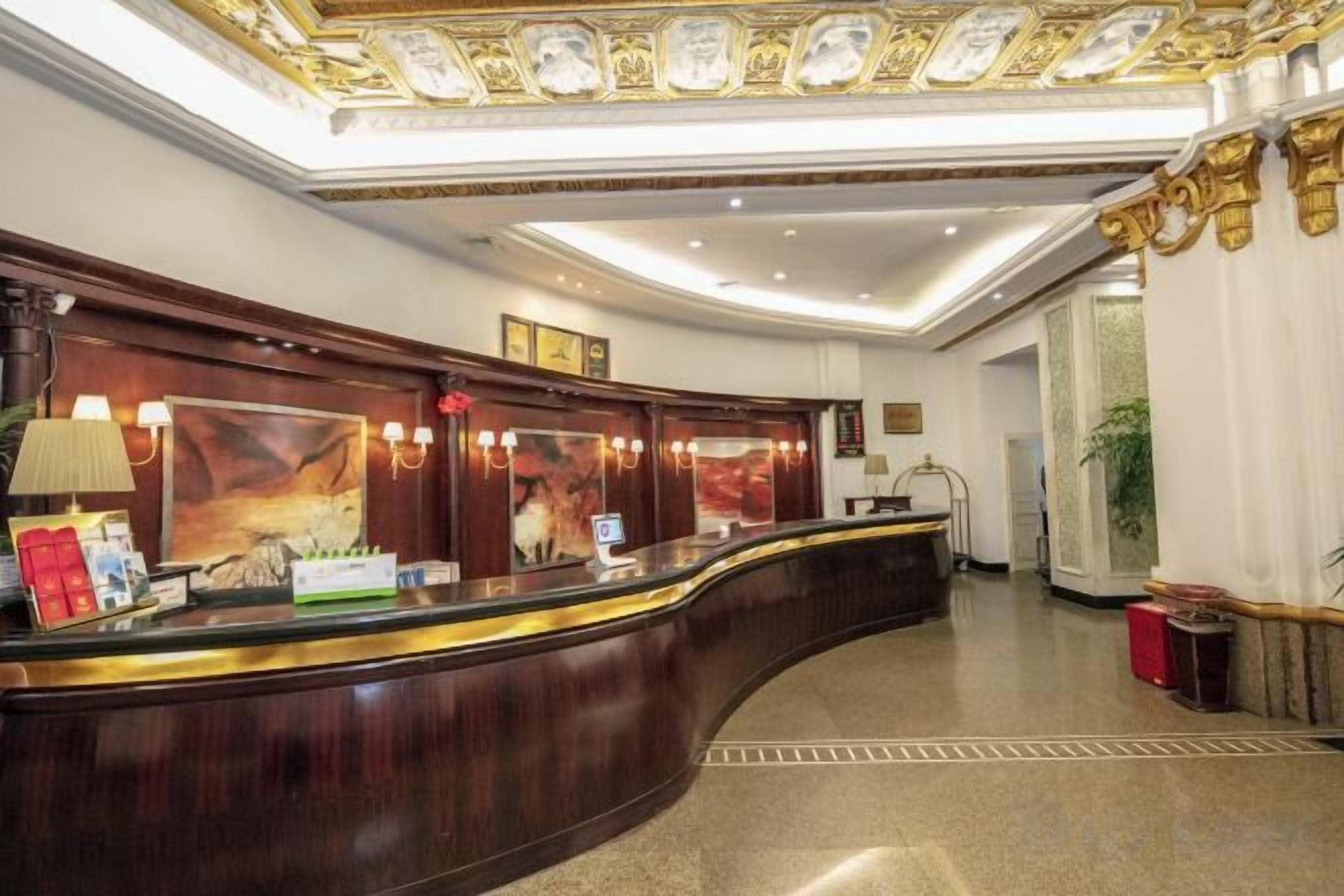 A reception area with a curved reception desk, framed artwork, and a chandelier.