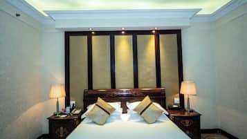 Una habitación de hotel con una cama grande, dos mesitas de noche y un cabecero con paneles verticales.