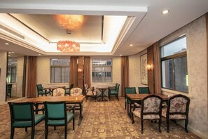 A hotel dining room with a high ceiling, patterned carpet, and a chandelier. - Huchuan Hotel (Yueqing)