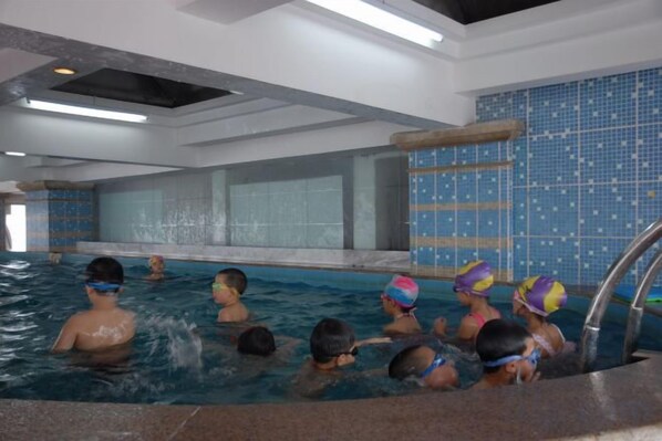 Una piscina interior con múltiples carriles, un muro de azulejos y una zona junto a la piscina.