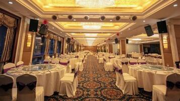 Un salón de banquetes con mesas redondas, sillas y una alfombra estampada.
