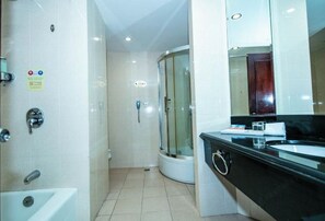 A modern bathroom with a glass-enclosed shower, a white sink, and a black countertop. - Huchuan Hotel (Yueqing)