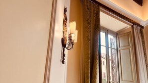Une pièce avec une fenêtre, un luminaire fixé au mur et une porte avec un rideau.