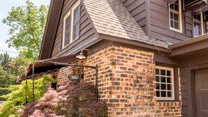 A two-story house with a brick facade, a sloped roof, and a garage.