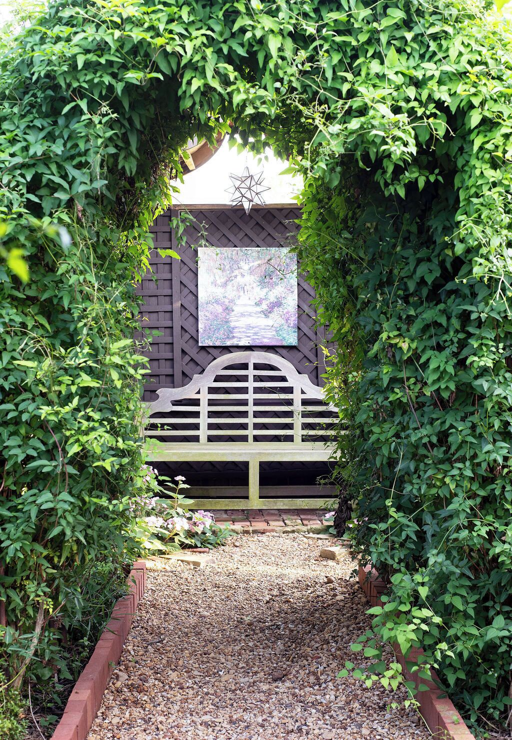 A garden pathway leading to a wooden bench with a decorative wall behind it.