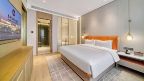 Ein modernes Hotelzimmer mit einem großen Bett, einem Schreibtisch und einem an der Wand befestigten Fernseher.