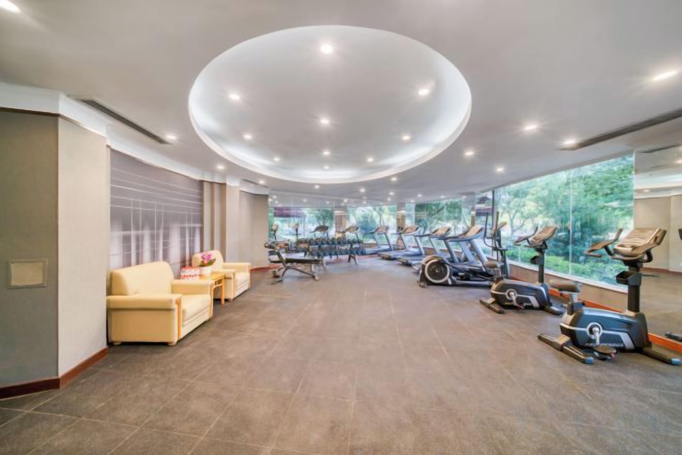 A spacious room with exercise equipment, a sofa, and a large window.