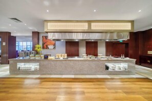 Un hall d’hôtel moderne avec un comptoir d’accueil central, une grande fenêtre et un mur décoratif.