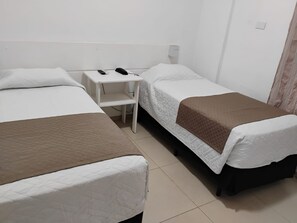 Habitación de hotel con dos camas, una mesita de noche y un teléfono.