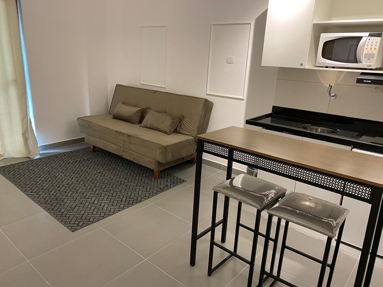 Een knus woongedeelte met een kitchenette, een bank en een eethoek.