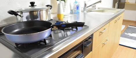 Een koelkast, een magnetron, kookgerei, borden en bestek