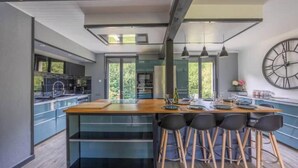 A modern kitchen with a central island, bar stools, and a large wall clock.