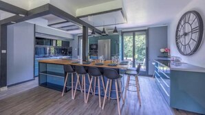 A modern kitchen with a central island, bar stools, and pendant lighting.