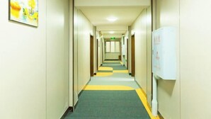 A hotel hallway with a carpeted floor, doors on both sides, and a whiteboard on the right wall. - Heihe Bianguan Mingyue Hotel (Heihe)