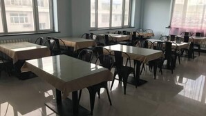 A dining area with tables and chairs, large windows, and a view of buildings outside. - Heihe Bianguan Mingyue Hotel (Heihe)