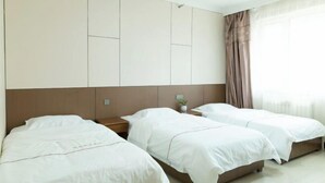 A hotel room with two single beds, a large wardrobe, a nightstand with a lamp, and a window with curtains. - Heihe Bianguan Mingyue Hotel (Heihe)
