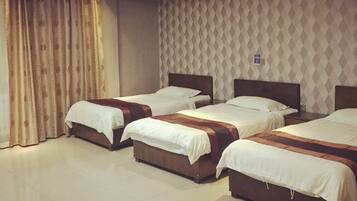 A hotel room with three beds, a patterned wall, and a curtain.