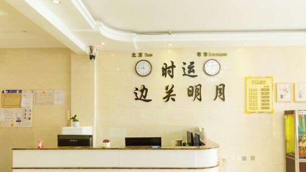 A reception desk with a clock, a wall with Chinese characters, and a bulletin board with notices. - Heihe Bianguan Mingyue Hotel (Heihe)
