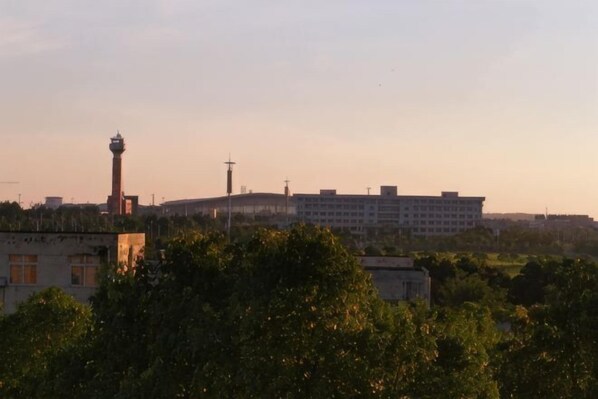 Un edificio con una torre, rodeado de árboles y otras construcciones.