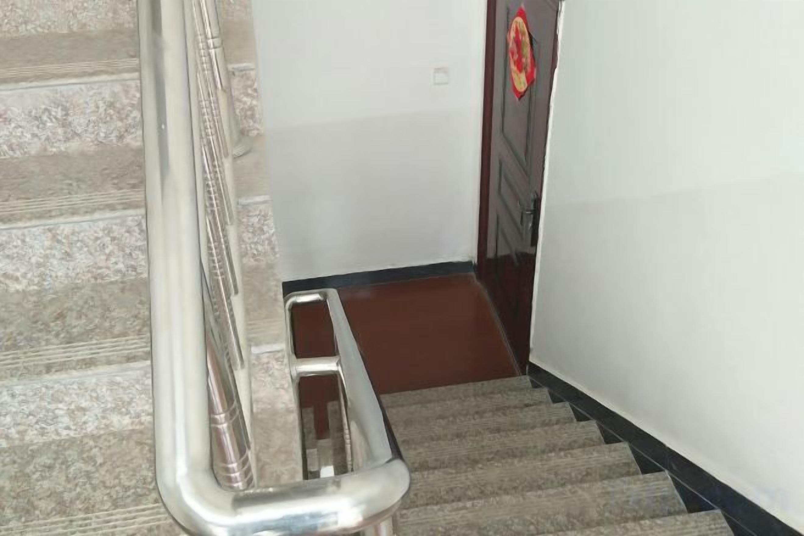 Una escalera alfombrada con barandilla de metal y una puerta de madera al final.