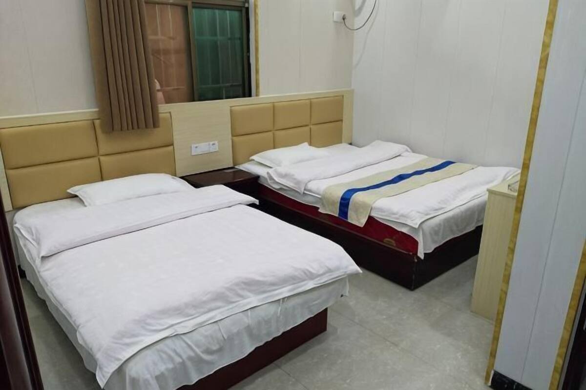 Habitación de hotel con dos camas, una ventana con cortinas, un teléfono instalado en la pared y una mesita de noche pequeña.