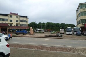 Uma área de estacionamento com vários veículos, incluindo carros e ônibus, e um edifício com uma placa.