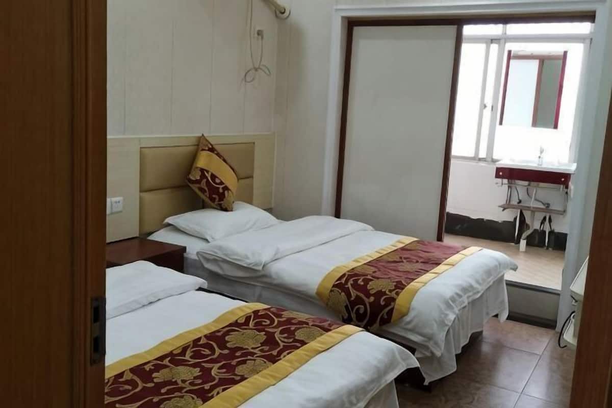 A hotel room with two beds, a bathroom, and a view of the outside.