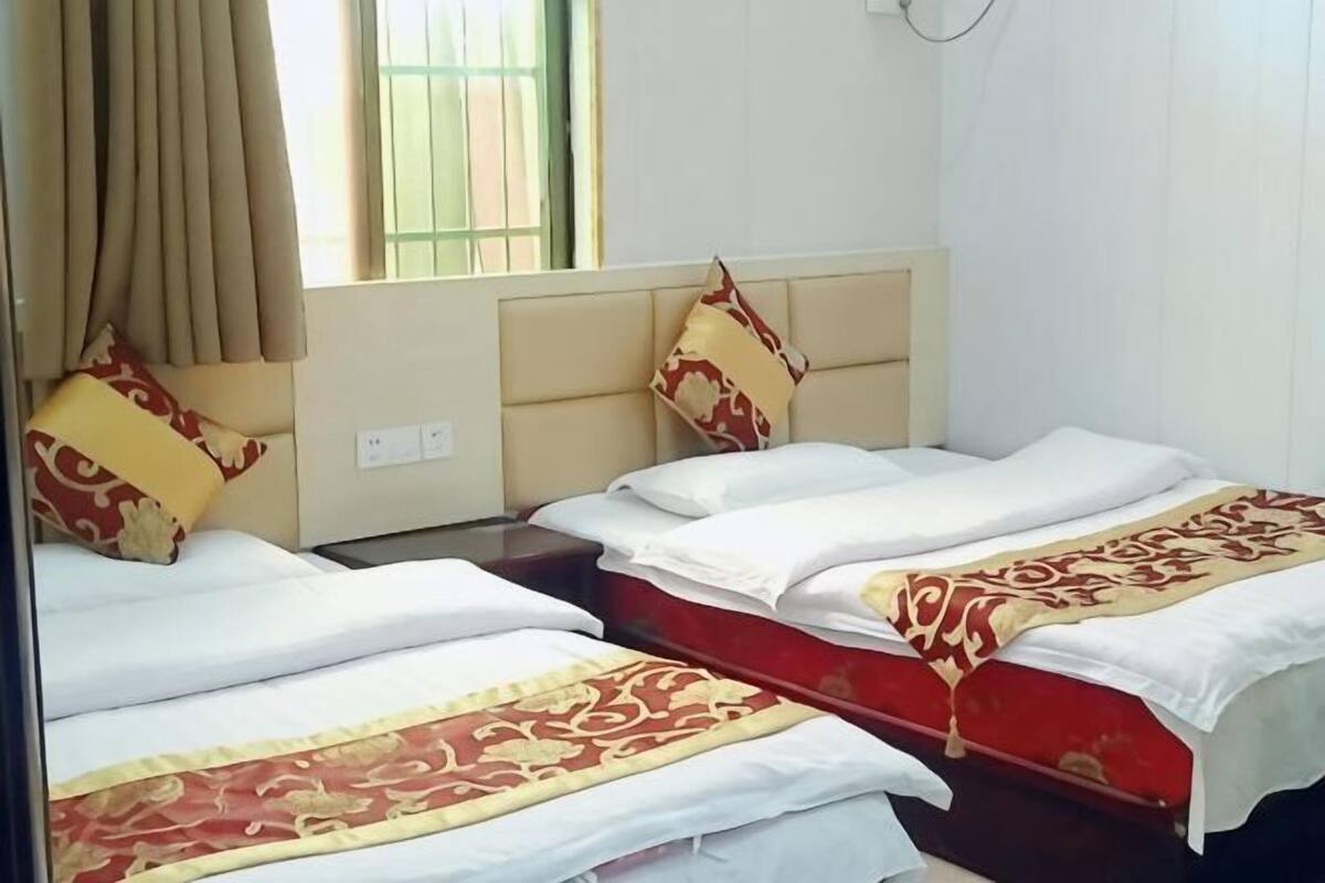 Una habitación de hotel con dos camas, una ventana con cortinas y un cabecero.