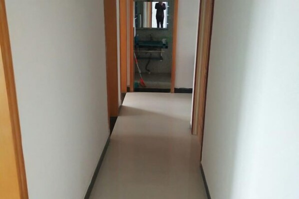 Un corridoio stretto con porte in legno su entrambi i lati, che conduce a una stanza con lavandino e specchio.