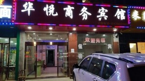 A hotel entrance with a neon sign, a car parked in front, and a visible reception desk. - Huayue Business Hotel Nanchang (Nanchang)