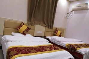 Two beds with headboards, a brown curtain, and an air conditioning unit on the wall.