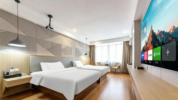 Habitación de hotel con dos camas, televisión, escritorio y ventana.