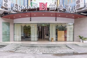 A hotel entrance with a glass facade, a red awning, and a sign above the entrance. - Borrman Hotel (Shaoguan The History East Street Fengcai Building) (Shaoguan)