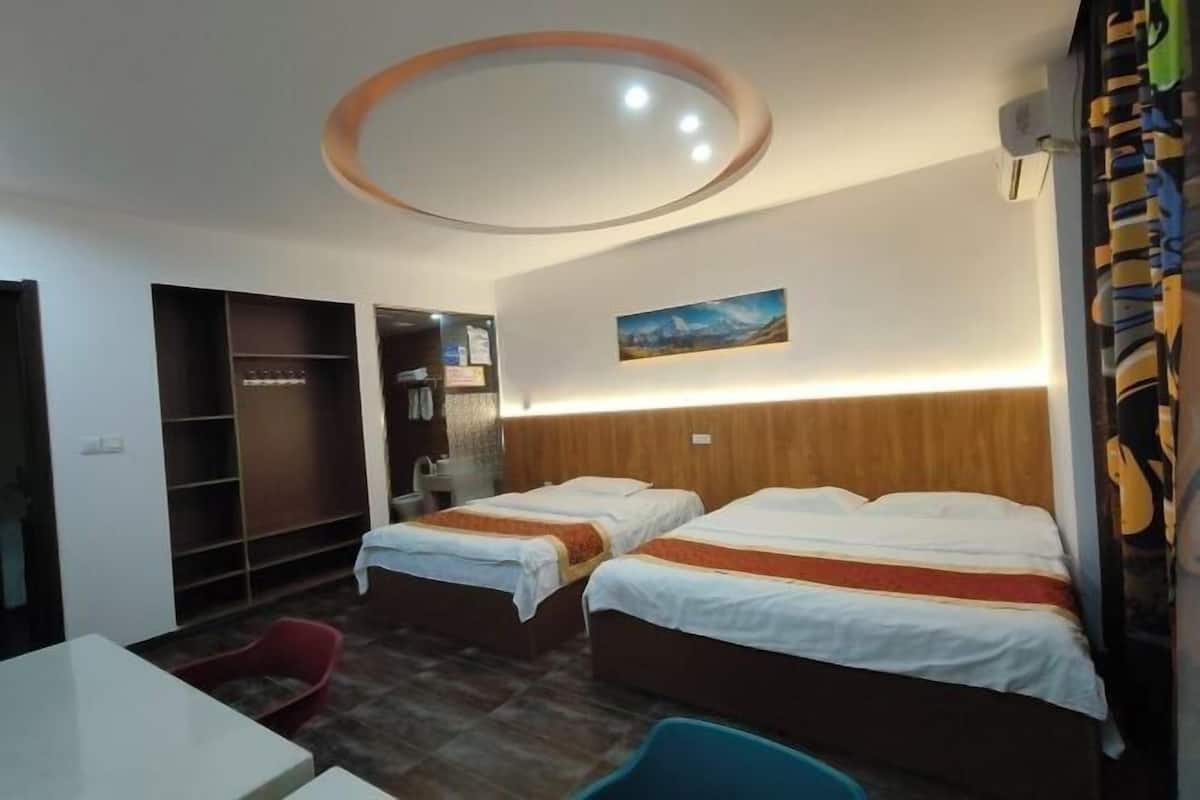 Ein Hotelzimmer mit zwei Betten, einem Schreibtisch, einem Stuhl, einem Kleiderschrank und einer runden Deckenleuchte.