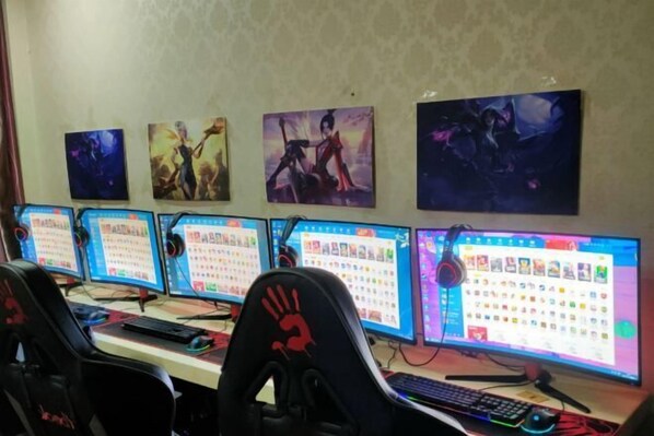 A gaming setup with multiple monitors, a keyboard, and a gaming chair. - Harbin Cashbox Express Hotel (Harbin)