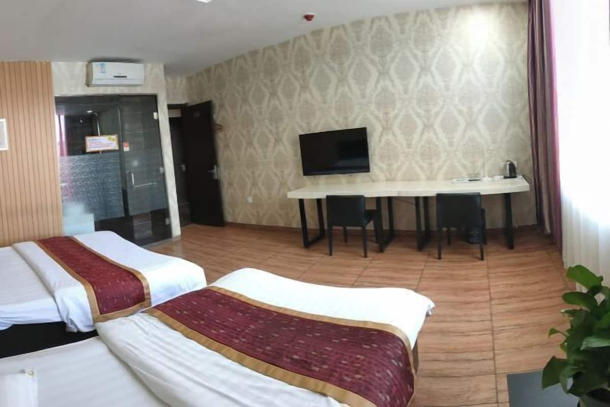 Ein Hotelzimmer mit zwei Betten, einem Schreibtisch, einem Fernseher und einem fenster mit Vorhängen.