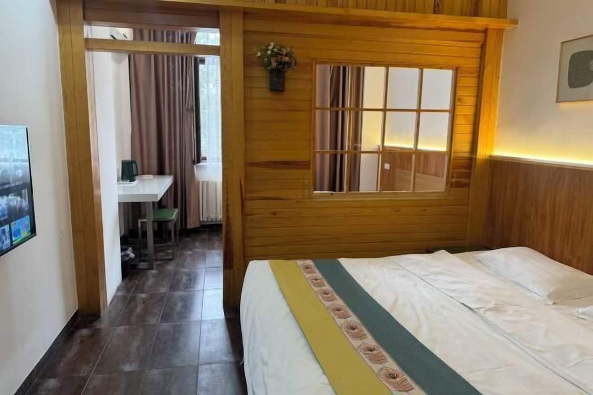 Ein Zimmer mit Holzwänden, einem Bett, einem Schreibtisch und einem Fenster.