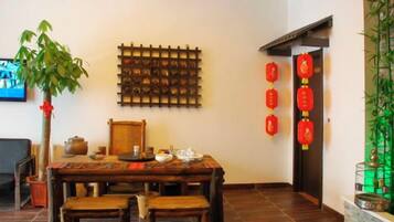 A traditional dining area with a wooden table and chairs, a wall-mounted tea set, and red lanterns.